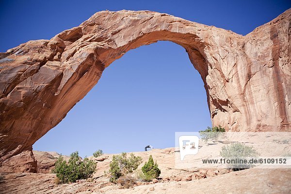 A girl mimics Corona Arch near Moab  Utah