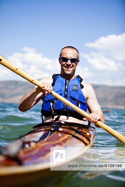 A man paddles a wooden kayak  Bear Lake.
