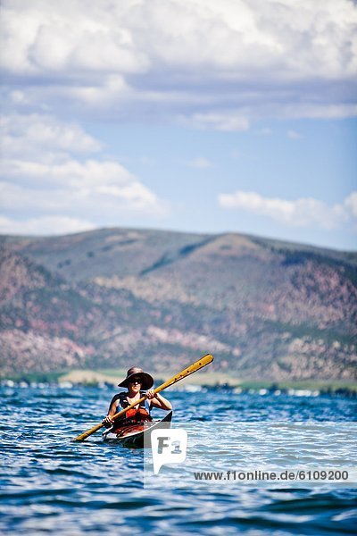 A woman paddles a wooden kayak  Bear Lake.