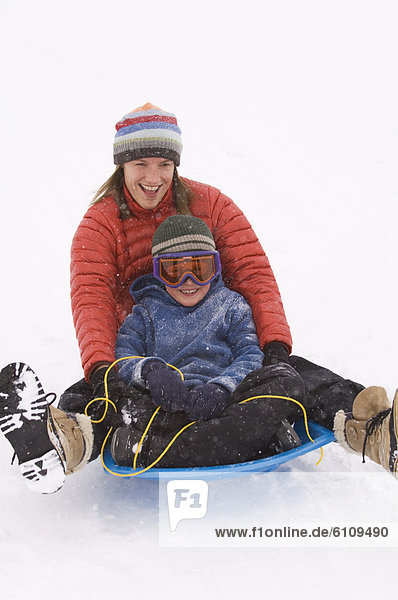 Mother and son sledding during snowstorm.