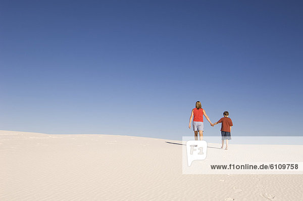 Mother and son hike across sand dunes