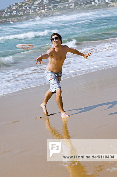 Man throwing frisbee on beach.