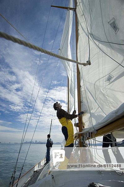 Man adjusts the rigging on his yacht.
