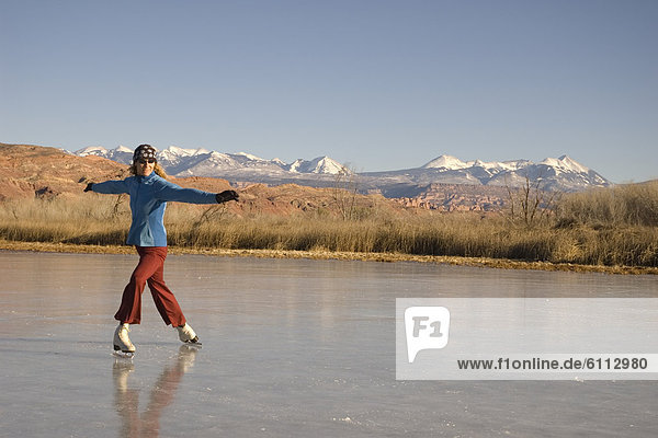 Woman ice skating on pond  Moab.