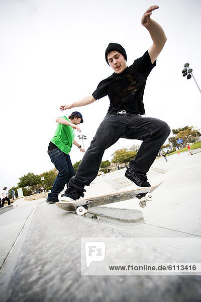 Two skateboarders do tricks at a skatepark.