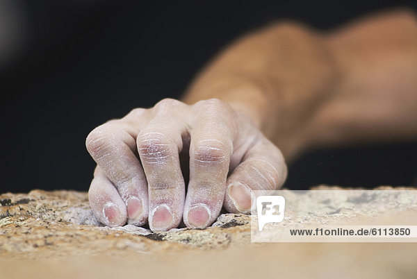 A rock climber's fingers grasp a small edge on a granite boulder near Bishop  California.