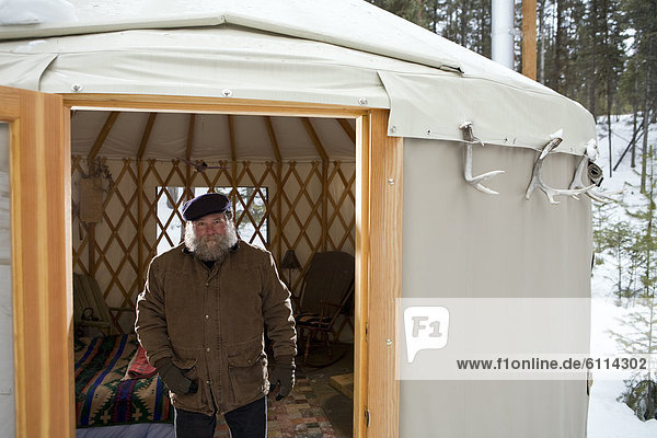 Bearded man with hat in sparse yurt  Whitefish  Montana.