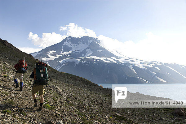 Two backpackers follow a trail around an alpine lake near the border of Chile and Argentina.
