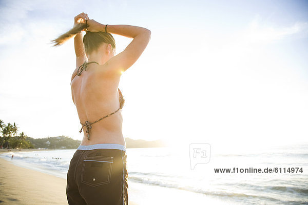 A young woman fixes her pony tail on a beach in Sayulita  Mexico.