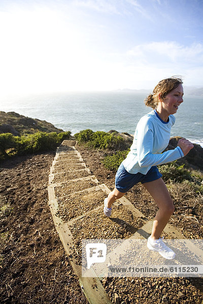 A woman running stairs near the ocean.