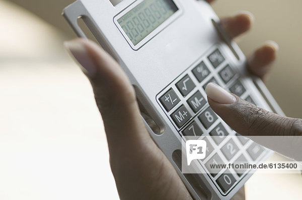 Close up of hands holding calculator