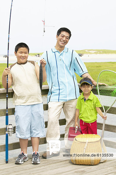 Portrait of father fishing with sons