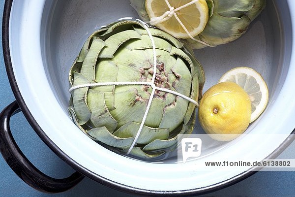 Two artichokes in cooking pot