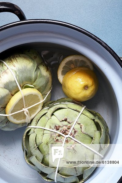 Two artichokes in cooking pot