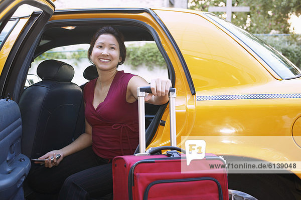Young woman with suitcase inside a cab