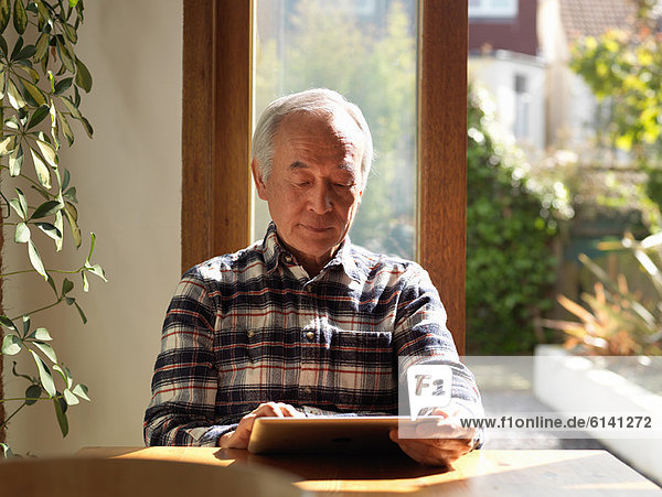 Older man using tablet computer at table