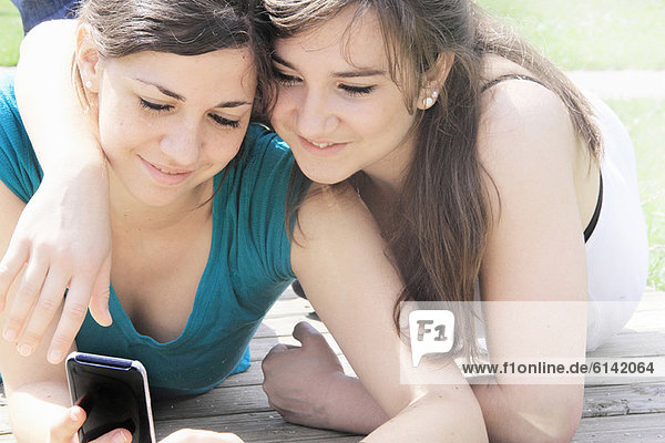 Teenage girls using cell phone outdoors