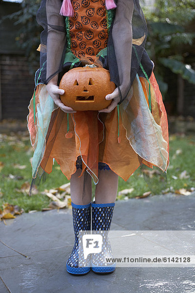 Girl in Halloween costume with pumpkin