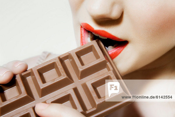 Junge Frau beißt Schokolade  Nahaufnahme  Mund