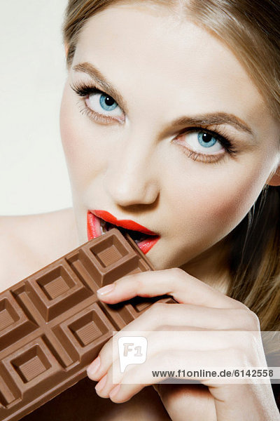 Junge Frau beißt Schokolade