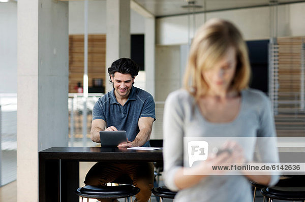 Businessman using digital tablet woman in foreground