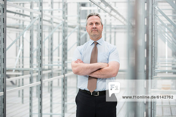 Man with arms folded in empty warehouse  portrait