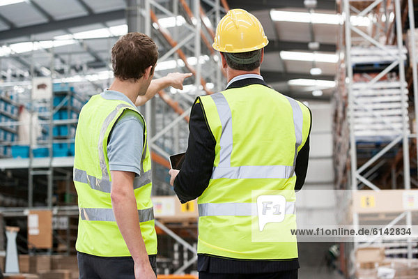 Two men in warehouse  one pointing