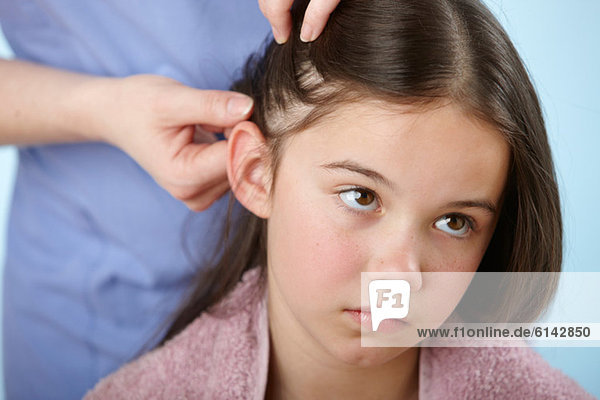 Eltern prüfen das Haar der Tochter auf Kopfschmerzen