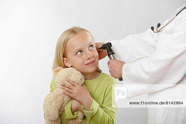 Doctor examining girl's ear