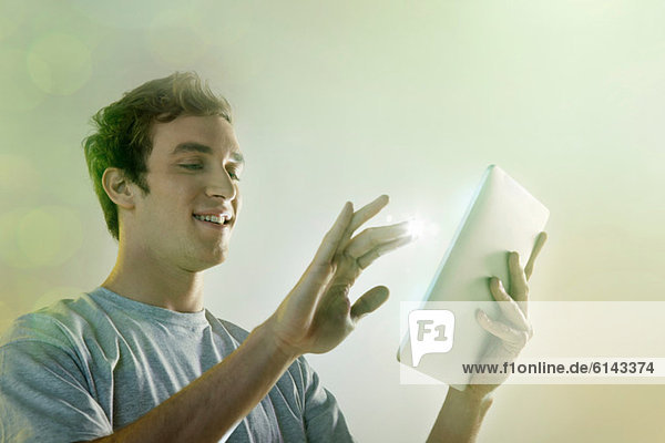 Junger Mann mit digitalem Tablett mit Beleuchtung