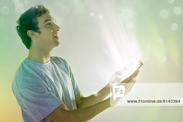 Junger Mann schaut auf das Licht kommende digitale Tablett