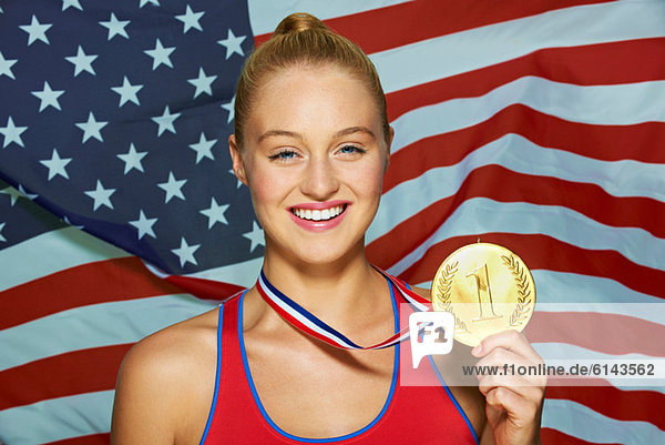 Junge Frau vor USA-Flagge mit Goldmedaille