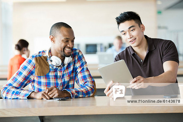 Young men in break room with digital tablet