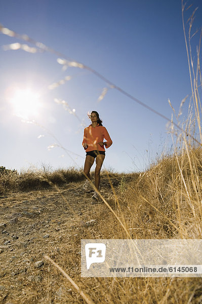 Full view of woman jogging on dirt road