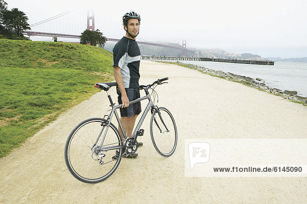 Portrait of man with bike with Golden Gate Bridge behind him