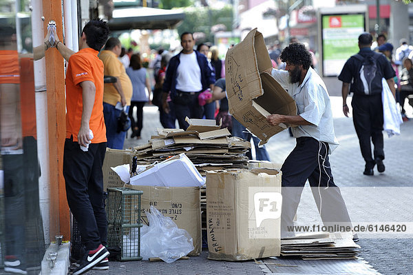 Poor man sorting recyclables or resources  cardboard boxes outside a shop  in order to sell them to a recycling plant  waste separation  pedestrian zone of San JosÈ  Costa Rica  Latin America  Central America