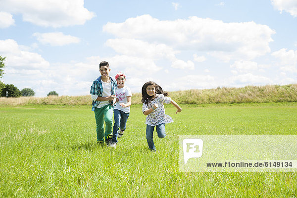 Three kids running over meadow