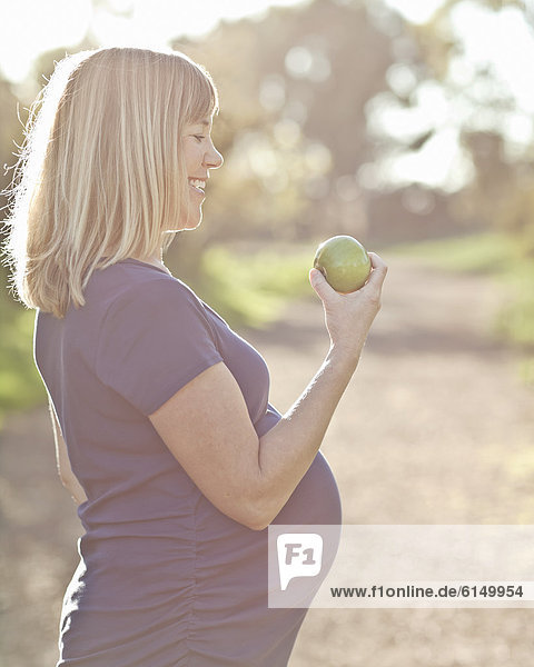 Außenaufnahme  Europäer  Frau  Schwangerschaft  Apfel  essen  essend  isst  freie Natur