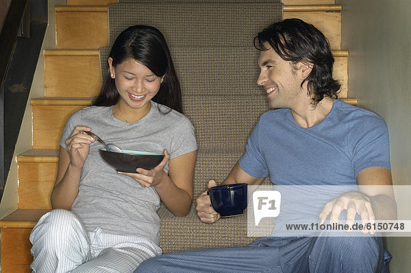 Multi-ethnic couple having breakfast on stairs