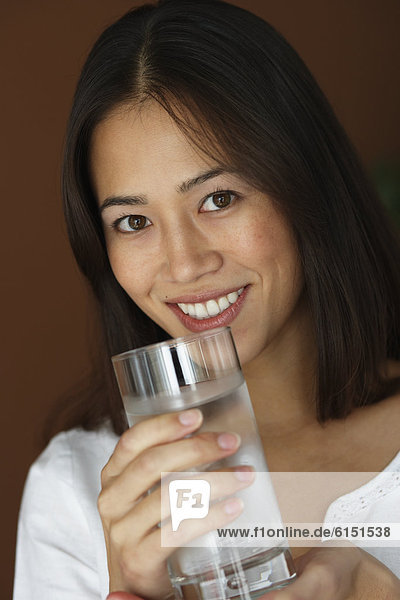 Asian woman holding glass of water