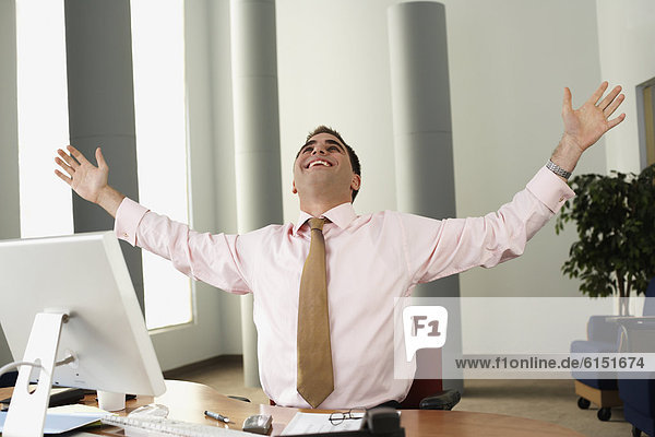 Middle Eastern businessman cheering at desk