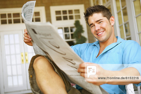 Junger Mann liest Zeitung