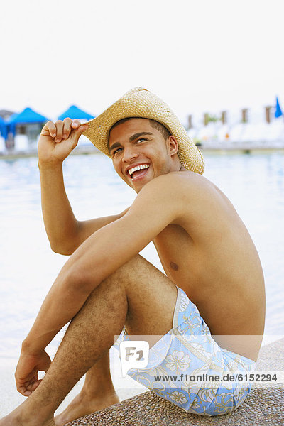 Hispanic man sitting next to swimming pool