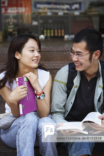 Young Asian couple holding school books