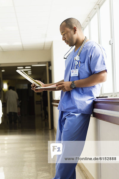 Black doctor looking at medical chart in hospital