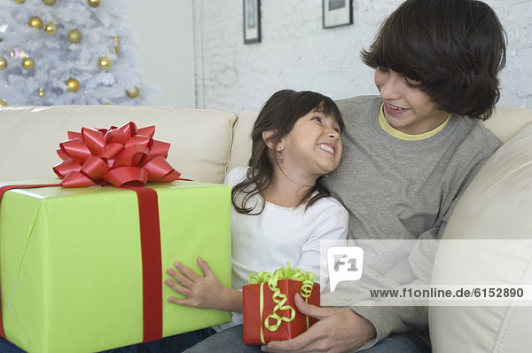 Hispanic brother and sister exchanging Christmas gifts
