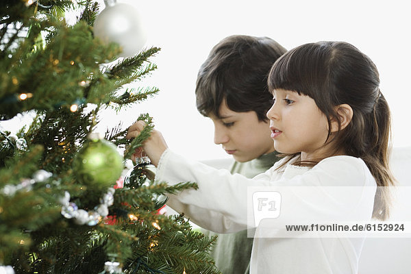 Hispanic brother and sister decorating Christmas tree