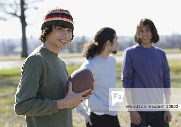 Hispanic boy holding football outdoors