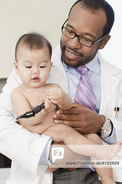 Doctor holding baby in doctor's office