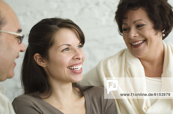 Hispanic parents and adult daughter laughing